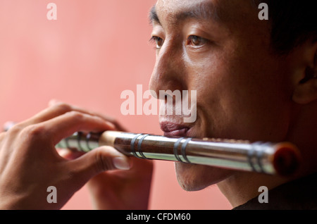 Primo piano di un giovane uomo cinese la riproduzione di un tradizionale Flauto Cinese a Pechino, Cina, Asia Foto Stock