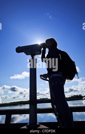 Donna che guarda attraverso un telescopio, bird watching, erboso si restringe Marsh, Hecla Isola Parco Provinciale, Manitoba, Canada. Foto Stock