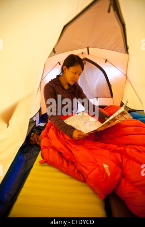 Una giovane donna si sveglia e piani il giorno mentre camping in Jasper Parco Provinciale, Alberta, Canada Foto Stock