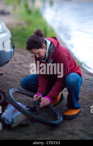 Una femmina di mountain biker pulisce il suo treno di trasmissione, Penticton, British Columbia, Canada Foto Stock