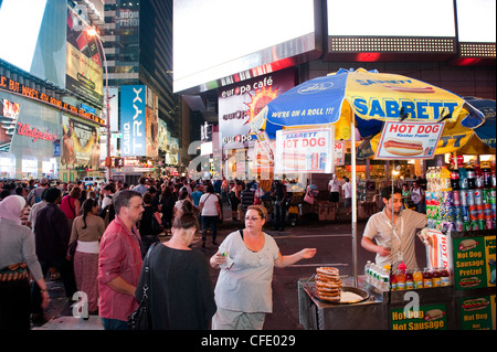 Le persone a un hot dog stand in un vivace Times Square a New York, di notte. Stati Uniti d'America. Foto Stock