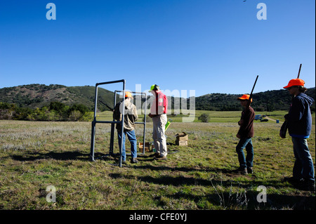 Un giovane cacciatore riceve istruzioni di fucile in corrispondenza di una argilla target range Foto Stock