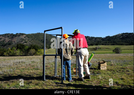 Un giovane cacciatore riceve istruzioni di fucile in corrispondenza di una argilla target range Foto Stock