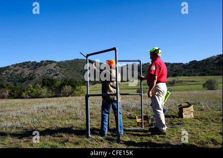 Un giovane cacciatore riceve istruzioni di fucile in corrispondenza di una argilla target range Foto Stock