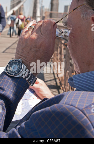 Un ben vestito uomo sul ponte di Brooklyn studi sua mappa. Foto Stock