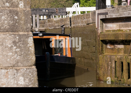 Archetto (anteriore) di narrowboat vela & la navigazione al di fuori del blocco di fondo di cinque serrature aumento - Bingley, Leeds Liverpool Canal, West Yorkshire, Inghilterra, Regno Unito Foto Stock