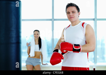 Ritratto di giovane uomo in rosso i guantoni guardando la fotocamera in palestra Foto Stock