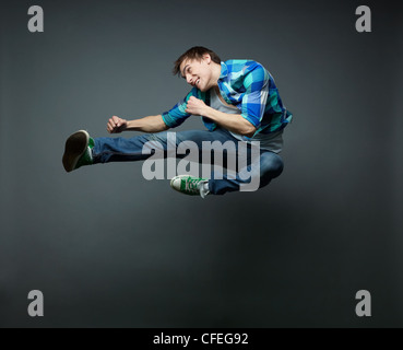 Energetic guy jumping con i pugni serrati stretto e calci l'aria Foto Stock