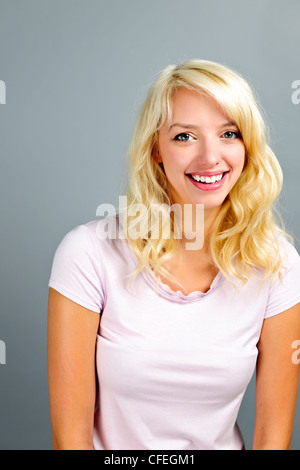 Ritratto di giovane sorridente bionda donna caucasica su sfondo grigio Foto Stock