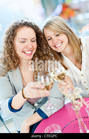 Due felici donne celebrando con bicchieri di vino bianco Foto Stock