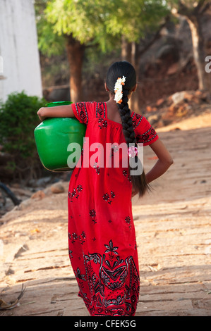 Rurale villaggio indiano ragazza adolescente che porta una pentola di acqua home. Andhra Pradesh, India Foto Stock