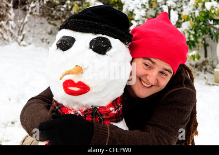 Giovane uomo che abbraccia un pupazzo di neve Foto Stock