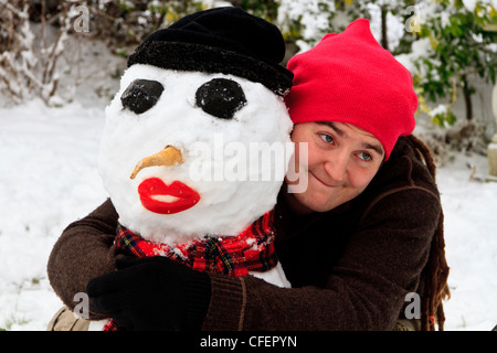 Giovane uomo che abbraccia un pupazzo di neve Foto Stock