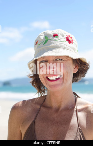Un sorridenti donna matura nei suoi anni quaranta indossando un cappello di estate sulla spiaggia. Foto Stock