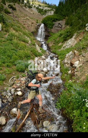 Backpacker attraversare un torrente in Oregon Wallowa della montagna. Foto Stock