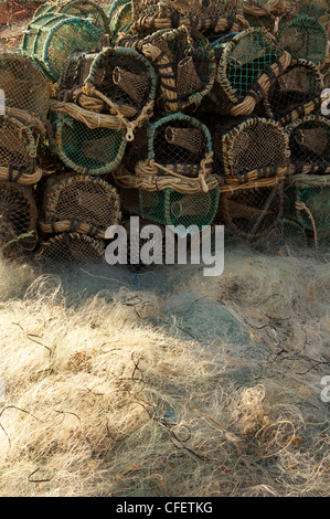 Pile di aragosta / pentole di granchio e pile di reti da pesca sulla banchina del porto di Poole Harbour nel Dorset, Inghilterra, Regno Unito. Foto Stock