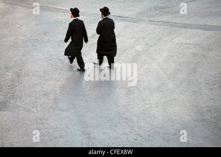 Due uomini Hasidic attraversamento cortile vuoto in rotta verso il Muro del Pianto a Gerusalemme, Israele Foto Stock