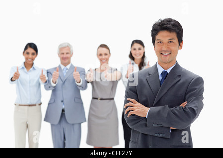 Close-up di un team aziendale con il loro pollice in su con un sorridente uomo asiatico attraversando le sue braccia Foto Stock