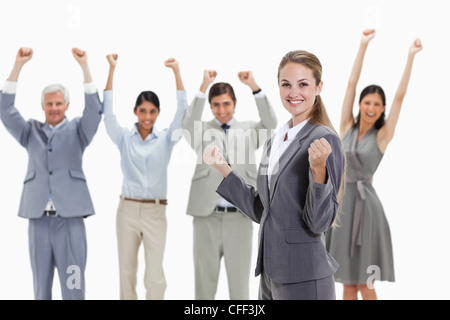 Donna bionda con la gente di affari alzando le braccia dietro di lei Foto Stock