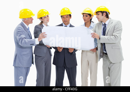 La gente di affari che indossa caschi di sicurezza guardando qualcosa su una mappa Foto Stock
