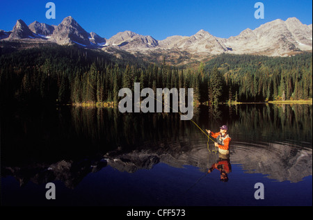 Giovane uomo la pesca con la mosca sull isola nel Lago la lucertola intervallo vicino al Fernie, British Columbia, Canada. Foto Stock