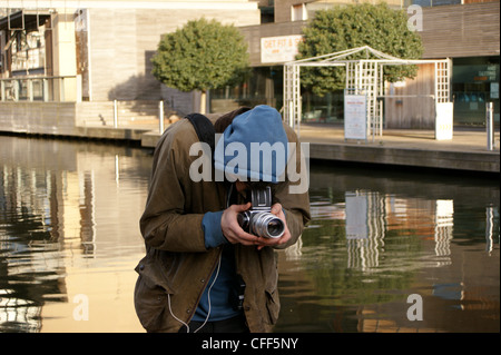 Uno studente di fotografia scattare una fotografia con una fotocamera Hasselblad su un canale alzaia in Londra Foto Stock