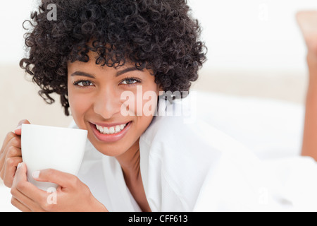 Donna sorridente tenendo una tazza di caffè Foto Stock