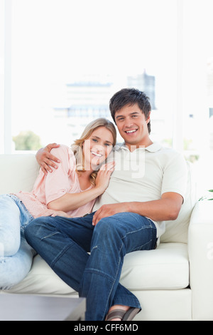 Uomo seduto e la donna che giace contro l'uomo, sorridente sul lettino Foto Stock