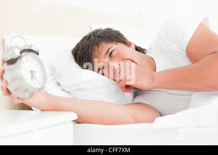 L'uomo svegliarsi, a sbadigliare e a prelevare la sua sveglia Foto Stock