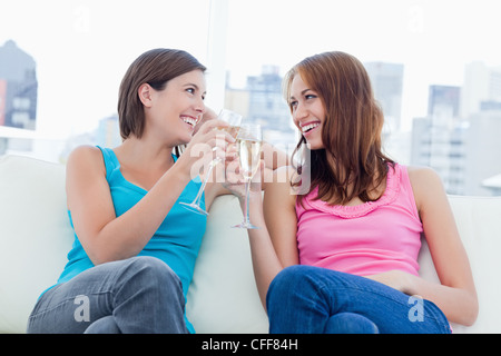 Giovani donne guardando gli uni con gli altri mentre il tintinnio di bicchieri di champagne Foto Stock