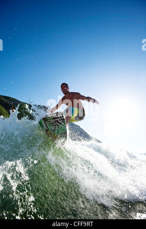 Un maschio atletico surf dietro un wakeboard barca su un lago in Idaho. Foto Stock