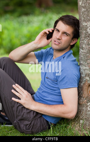 Giovane serio parlando al telefono mentre guardando la telecamera Foto Stock