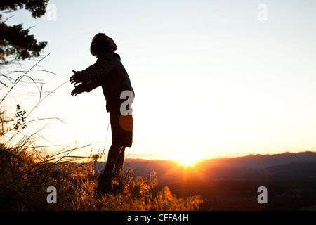 Un giovane uomo saluta la mattina su una escursione come il sorgere del sole su una valle in Idaho. Foto Stock