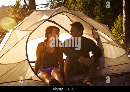 Un felice giovane adulto giovane sorridere e ridere su un viaggio di campeggio accanto a un lago in Idaho. Foto Stock