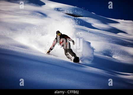 Un athletic snowboarder rip di polvere fresca si trasforma nel backcountry in una giornata di sole in Colorado. Foto Stock