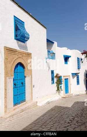 Idi Bou Said. La Tunisia. Vista del tipico abbastanza tranquillo vicolo ciottoli rivestiti con pareti dipinte di bianco e porte blu e blu Foto Stock