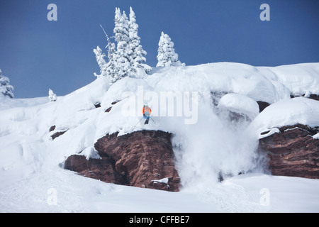 Un athletic sciatore salta fuori da una scogliera nel backcountry su una soleggiata giornata di polvere in Colorado. Foto Stock