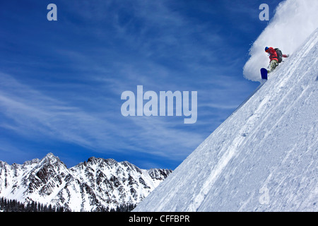 Un athletic snowboarder rip di polvere fresca si trasforma nel backcountry in una giornata di sole in Colorado. Foto Stock