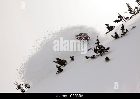 Un athletic snowboarder lacerazioni profonde fresco in polvere si trasforma nel backcountry su un giorno di tempesta in Montana. Foto Stock