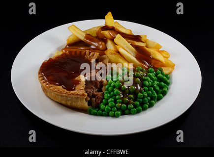 Close up della bistecca torta e patatine con piselli e sugo di carne. Un tradizionale piatto britannico Foto Stock