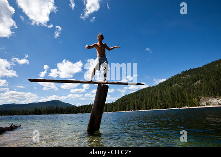 Un giovane uomo saldi su un teeter totters alta al di sopra di un lago in Idaho. Foto Stock