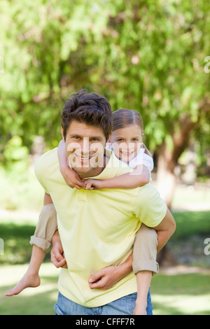 Una figlia sorrisi mentre ottenere un piggyback Foto Stock