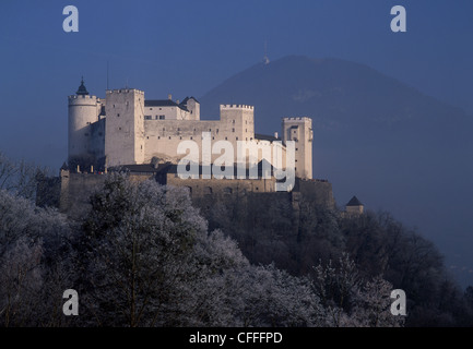 La fortezza Hohensalzburg sopra città di Salisburgo in inverno con la brina su alberi e nebbia sulla montagna dietro a Salzburg Austria Foto Stock