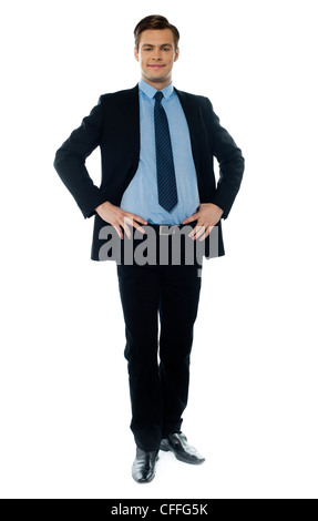 Elegante giovane dirigente in business suit in posa con le mani sulla sua vita Foto Stock
