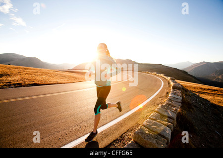 Un atletico donna corre lungo Trail Ridge Road (12,183 piedi) vicino al suo apice di sunrise, Rocky Mountain National Park, Colorado. Foto Stock