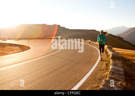 Un atletico donna corre lungo Trail Ridge Road (12,183 piedi) vicino al suo apice di sunrise, Rocky Mountain National Park, Colorado. Foto Stock