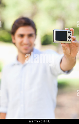 Telecamera essendo utilizzato da uomo sorridente per scattare una foto di se stesso Foto Stock