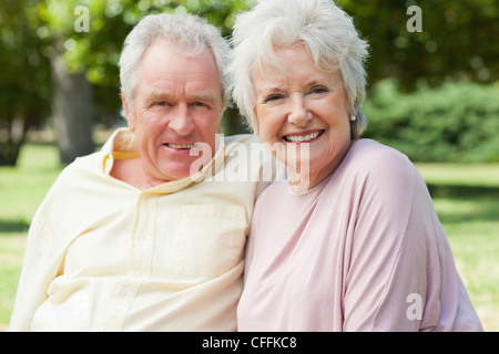 Due amici di sorridere quando essi siedono accanto a ogni altra in un parco Foto Stock