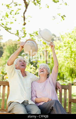 Due amici a elevare i loro cappelli mentre è seduto su una panchina Foto Stock