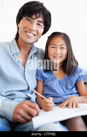 Un padre e figlia guardare avanti e sorridere mentre si fanno i compiti Foto Stock